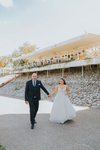 A vertical shot of a beautiful bridge and groom walking holding hands