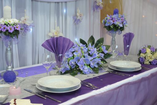 A close-up shot of an elegant table setting with glasses and flower arrangements in purple