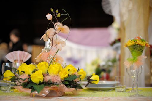 A close-up shot of an elegant table setting with glasses and yellow flower arrangements