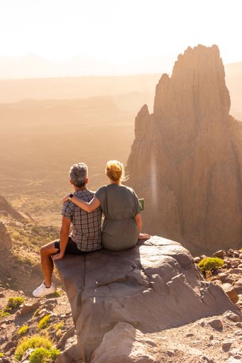 A vertical shot of married couple watching the sunset in the natural area of Teide in Tenerife, Canary Islands