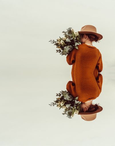 A vertical shot of a child holding a bouquet of flowers with her upside down reflection below