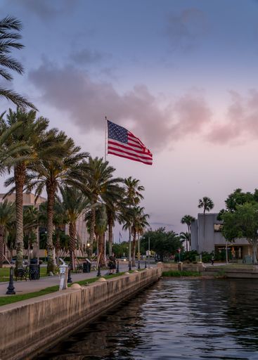 A vertical shot of USA flag with palms on Sanford Riverwalk and Marina during Sunset