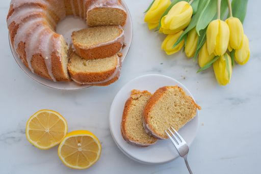 A top view of sweet vanilla thyme sponge cake and yellow tulips on a white table