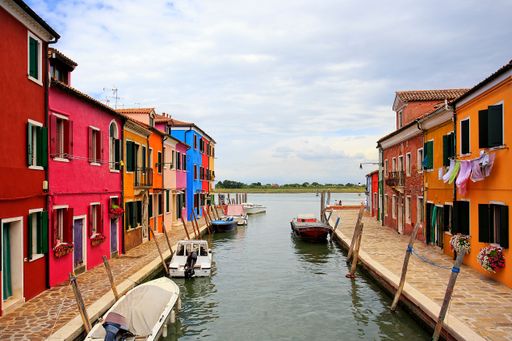 A scenic view of boats moored at a canal between colorful buildings in Burano, Venice, Italy