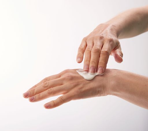 A woman applying cream on hand on isolated white background