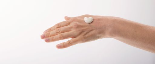 A woman applying cream on hand on isolated white background
