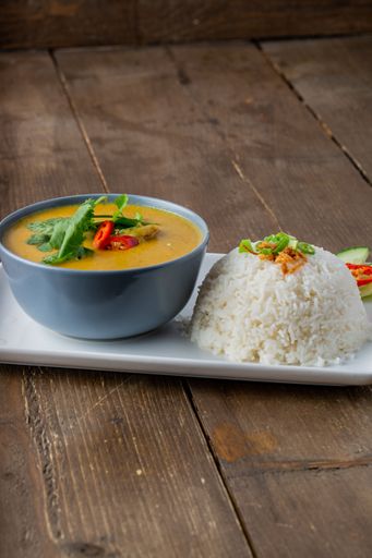 A vertical shot of Thai chicken soup with rice on wooden table