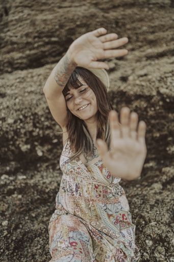 A closeup of a young caucasian female with tattoos wearing a dress and straw hat