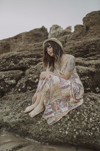 A selective focus shot of a young caucasian female with tattoos wearing a dress and straw hat