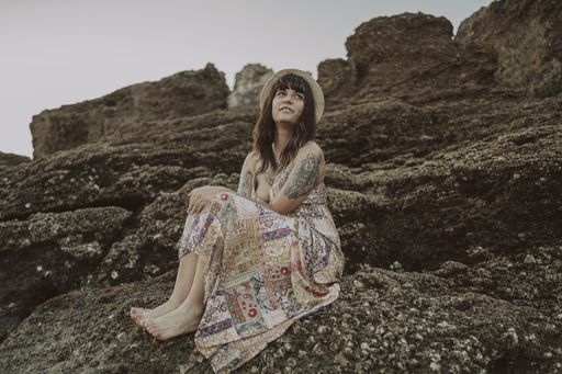 A selective focus shot of a young caucasian female with tattoos wearing a dress and straw hat