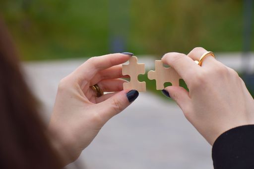 Young female hands holding two pieces of jigsaw puzzle-business concept and unity