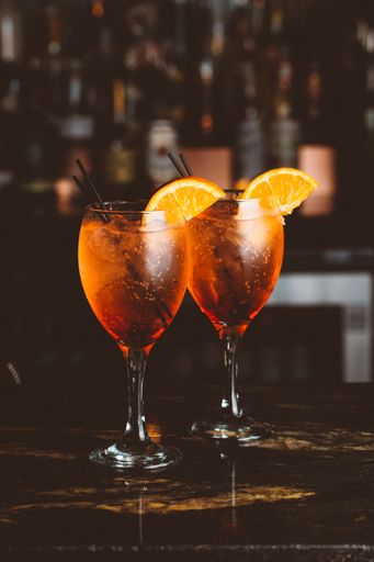 A vertical shot of two glasses of Aperol Spritz on bar counter