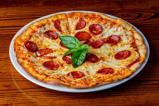 The delicious pepperoni pizza with basil leaves on wooden table