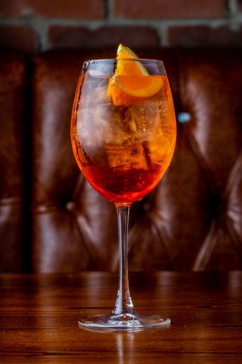 A vertical shot of a glass of Aperol Spritz on bar counter
