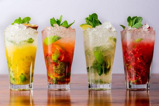 A variety of mojitos in a row on wooden table