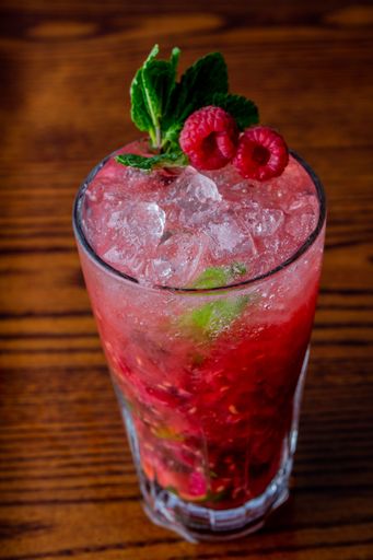 A vertical closeup of Raspberry mojito on wooden table