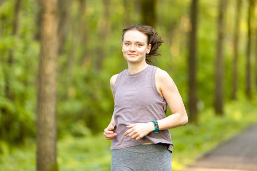 A young Caucasian female running on the path through the forest