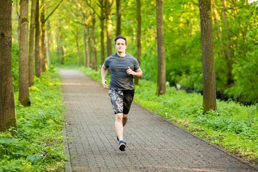 A young Caucasian male running on the path through the forest