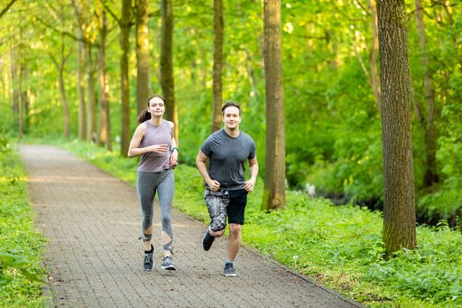 The two Caucasian young male and female running on the path through the forest