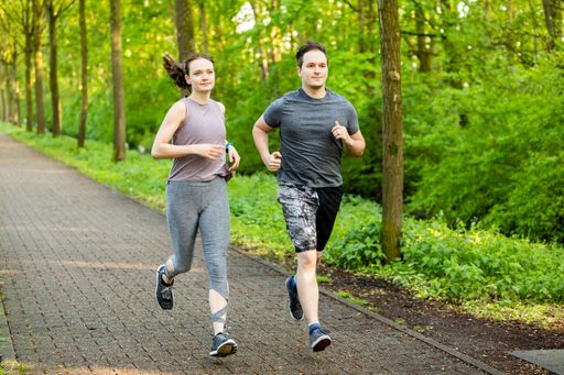 The two Caucasian young male and female running on the path through the forest