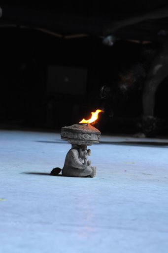 A vertical shot of a small sculpture resembling an Aztec gold with burning fire on the top