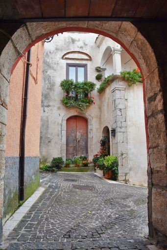 A vertical shot of a narrow street in Fornelli village in the Molise region, Italy seen through an arch