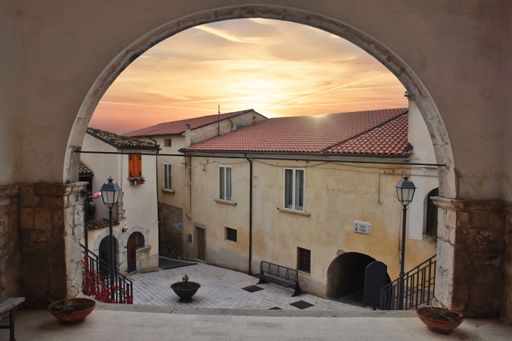 A scenic view of the sunset seen through an arch in a narrow street in Fornelli village of Molise region, Italy