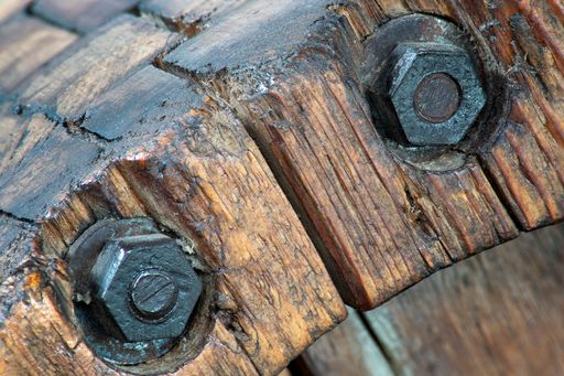 A selective focus shot of rusty bolts on wooden texture