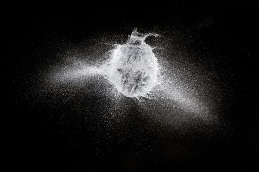 A high-speed shot of the explosion of a balloon filled with water on a black background