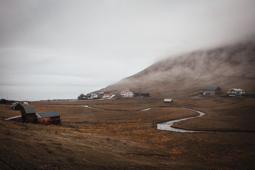 A beautiful scenery of a river surrounded by rocky cliffs under a cloudy sky in the Faroe Islands