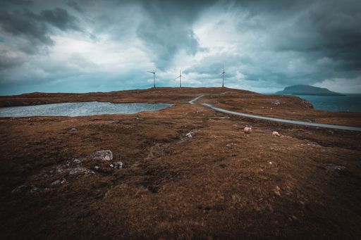 A beautiful scenery of a river surrounded by rocky cliffs under a cloudy sky in the Faroe Islands