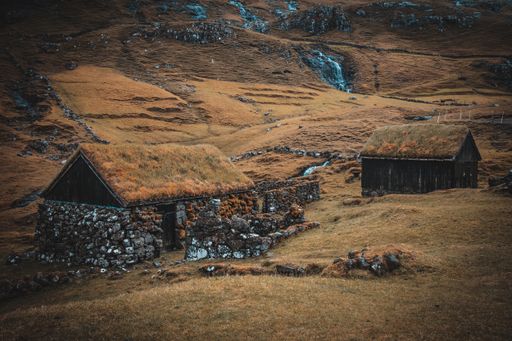 A high angle shot of buildings by the lake surrounded by rocky cliffs in the Faroe Islands