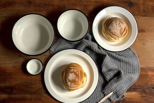 A top view of artisan style bowls, plates and breads on wooden table