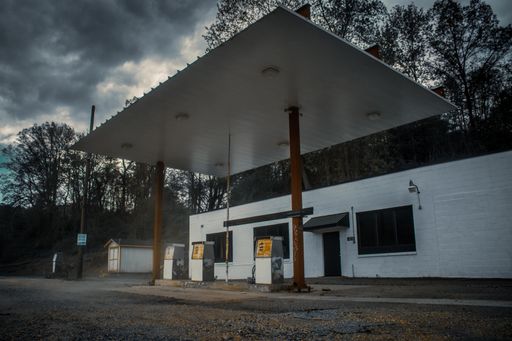 An abandoned gas station under dark clouds