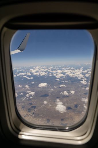 A vertical shot of a beautiful view with clouds from an airplane window