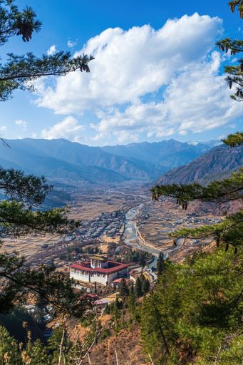 A vertical high angle shot of Paro Dzong, The National Museum of Bhutan with a magnificent mountainous view behind