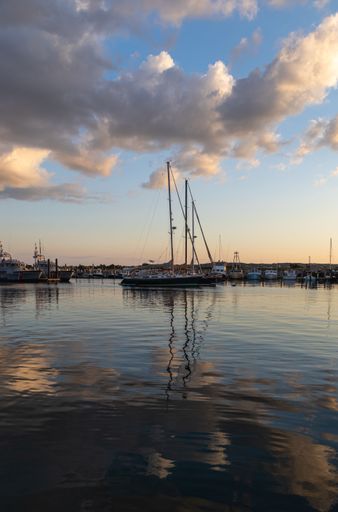 A vertical shot of sailboats in a port during a beautiful sunset