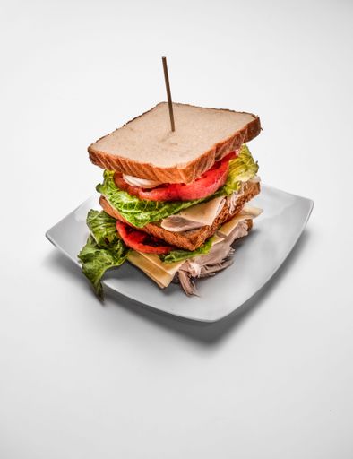 A vertical shot of a club sandwich on a white background