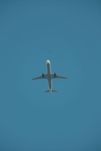 A vertical shot of an airplane flying high in the blue sky