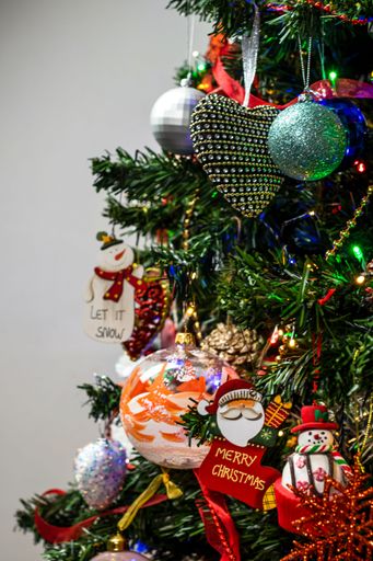 A vertical closeup of beautiful ornaments hanging on the Christmas tree.