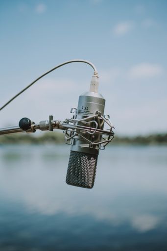 A vertical shallow shot of a gray recording microphone with a wire and a stand on a blurred blue background