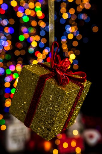 A vertical shot of glittery Christmas present ornament against bokeh lights background