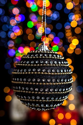 A vertical shot of a Christmas black ball decoration with bokeh Christmas lights
