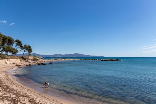 The beautiful Costa Brava beach in Spain on a sunny summer day with a woman coming out of the water