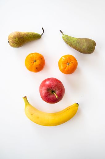 A vertical closeup of various fruits isolated on white background. A smiley face.