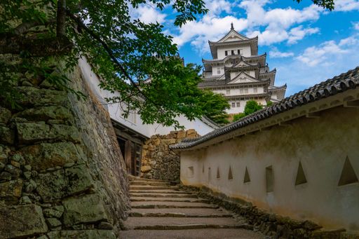 A footpath with stony staircases in background of Himeji castle under blue bright sky