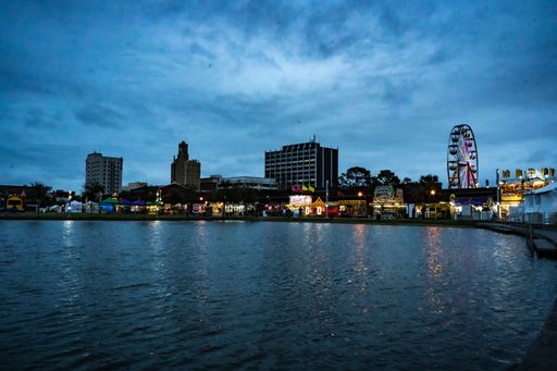 A cloudy evening with a glowing carnival in distance along the shore in downtown Beaumont, Texas, United States