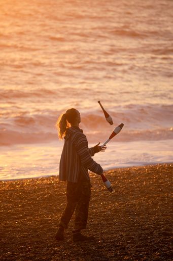 A closeup of a girl doing acrobatics on the beach at sunset by the sea in Brighton, UK