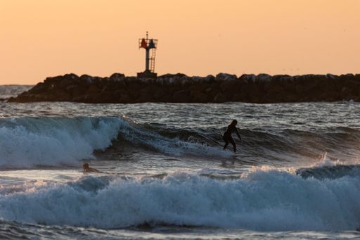 A young male surfing on the water at sunset in San Diego, California