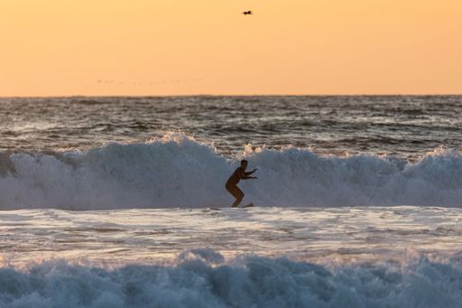 A young male surfing on the water at sunset in San Diego, California